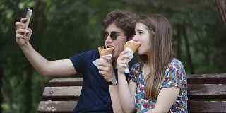 年轻情侣在公园里吃冰淇淋，然后自拍