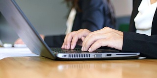 近距离的商业女性在笔记本电脑键盘上打字会议记录在会议室