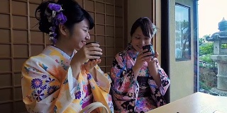 年轻的日本女性穿着传统和服喝茶