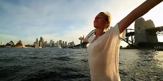 Young woman arms outstretched at Sydney harbour