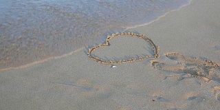 心的形状在沙子被海浪冲走