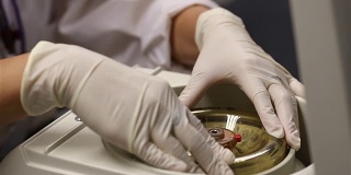 封闭的女科学家装载小瓶液体到一个实验室的离心机。