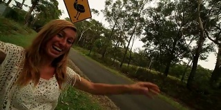 年轻女子站在鸸鹋警告标志附近的自拍，澳大利亚