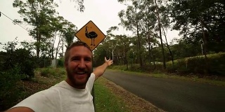 年轻男子站在鸸鹋警告标志附近的自拍，澳大利亚