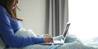 年轻女性在床上用笔记本电脑工作，在家工作