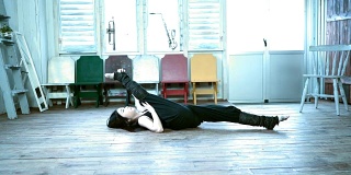 年轻的舞蹈演员躺在木地板上伸直双腿