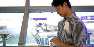 一名男子在机场候机厅使用笔记本电脑