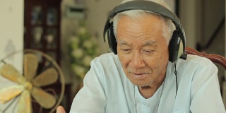 快乐的亚洲老人耳机在家听音乐