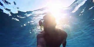 一个年轻人在潜水，阳光照耀着海面