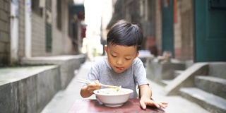 快乐的亚洲孩子用筷子吃美味的面条