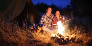 年轻夫妇在篝火上准备晚餐