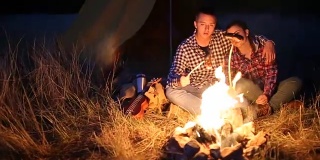 年轻夫妇在篝火上准备晚餐
