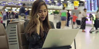 年轻的亚洲女子在机场使用笔记本电脑
