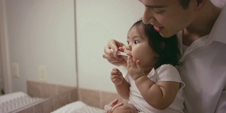 给婴儿刷牙的民族父亲