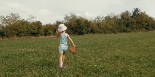一个女孩在夏天的绿地上奔跑。真实的人，乡村场景。