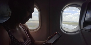 一名年轻女子在飞机上看电子书