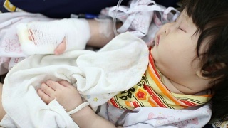 生病的婴儿在医院的安全座椅上接受生理盐水治疗视频素材模板下载