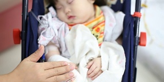 生病的婴儿在医院的安全座椅上接受生理盐水治疗