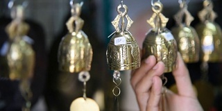 一名泰国游客在纪念品商店选购铃铛。