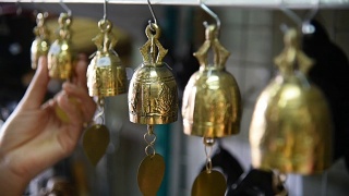一名泰国游客在纪念品商店选购铃铛。视频素材模板下载