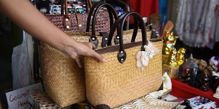 一名女性游客在泰国的纪念品商店选择手工包。