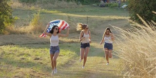 十几岁的女孩举着美国国旗跑步庆祝独立日