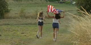 十几岁的女孩举着美国国旗跑步庆祝独立日