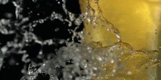 水滴落在装满啤酒的玻璃杯上。新鲜的比喻