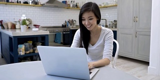 Woman working from home very happy on her laptop美丽的亚洲女人在家工作非常开心在她的笔记本电脑上
