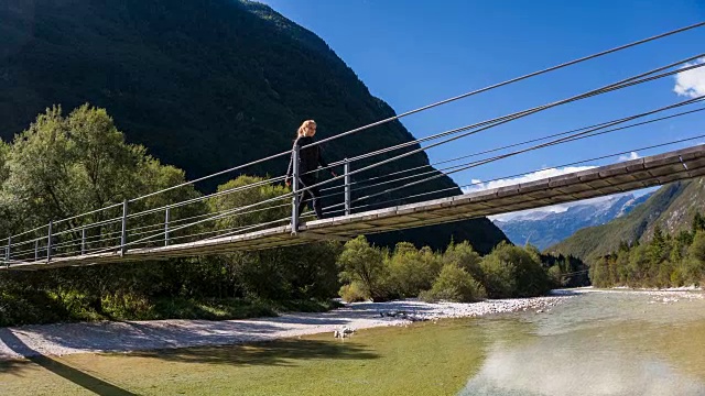 一名年轻女子正穿过山间溪流上的木吊桥