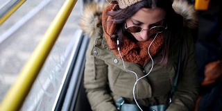 一个女人在无轨电车上用智能手机听音乐