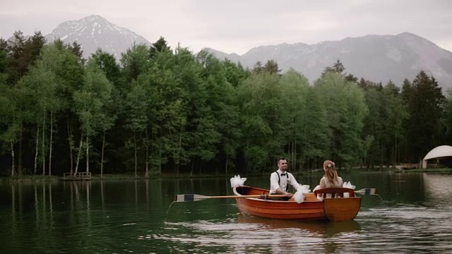 SLO MO新娘和她的新郎乘坐一艘船穿过一个湖