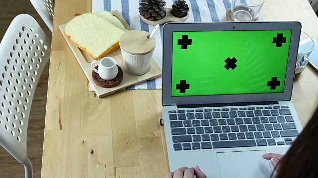 Over the Shoulder view of Woman Using Laptop with Green screen with Breakfast, Chroma key