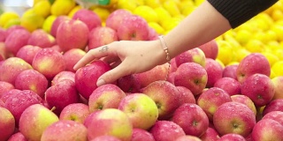年轻女子在超市挑选苹果