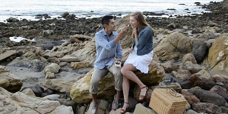 多民族浪漫情侣在海滩吃寿司