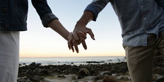 在海滩上牵着手的多民族浪漫情侣