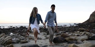 多民族浪漫情侣在海滩上散步