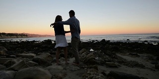 多民族浪漫情侣在海滩上看日落