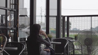 年轻的亚洲女人在咖啡馆里打电话视频素材模板下载