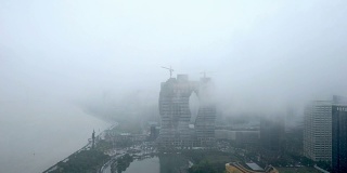 从俯视图看，河附近的现代建筑雾气蒙蒙