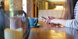 女人用智能手机，在咖啡店喝咖啡