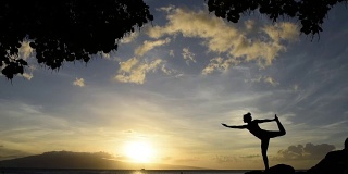 日落时分，年轻女子在海边做瑜伽
