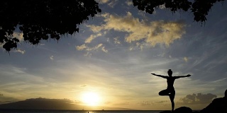 Young woman doing oceanside yoga at sunset