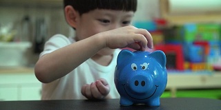 小男孩把一枚硬币放进扑满——孩子为未来存钱的概念