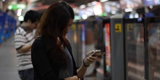年轻的亚洲女性在公共交通工具上使用智能手机