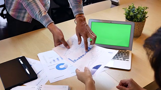 两个商业人士用绿屏笔记本电脑分析财务报告