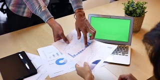 两个商业人士用绿屏笔记本电脑分析财务报告