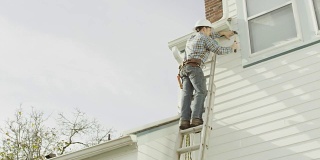 建筑工人爬上梯子，在住宅上干活