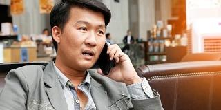 一个亚洲男人坐着打手机