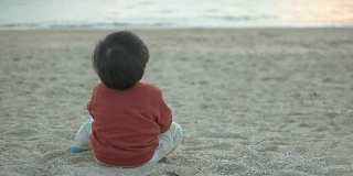 婴儿坐在海滩上。